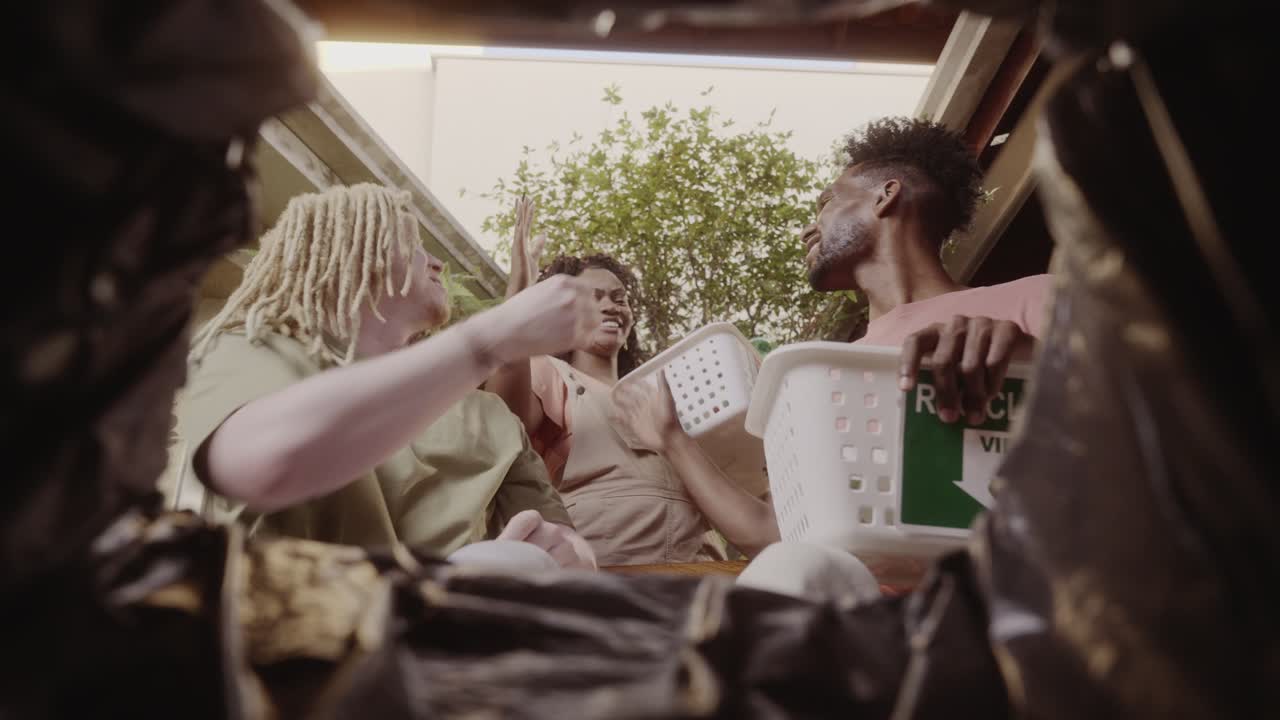 Friends recycling glass waste from inside a bin