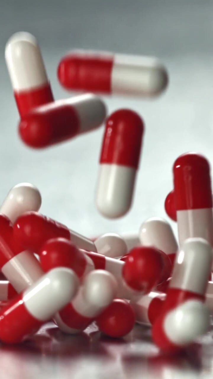 Capsule rosse e bianche che cadono al rallentatore.