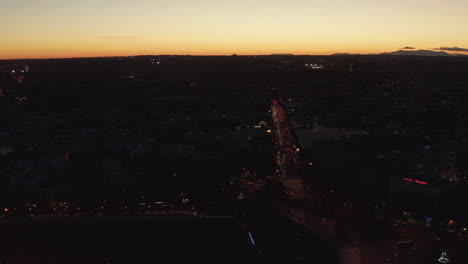 Aerial-panoramic-footage-of-traffic-in-streets-of-city.-Dark-scene-contrasting-with-bright-sunset-sky.