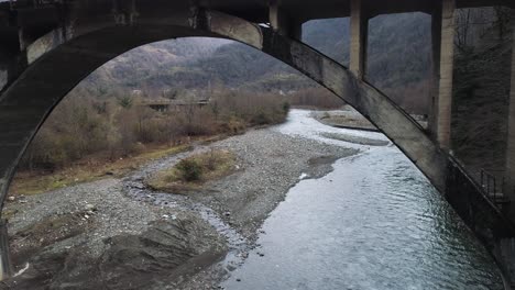 old concrete arch bridge over a river in the mountains