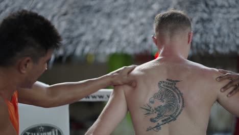 muay thai fighter with tiger tattoo receiving a pre-training massage