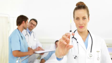 los médicos hablan con el paciente enfermo en la cama mientras la enfermera prepara la jeringa
