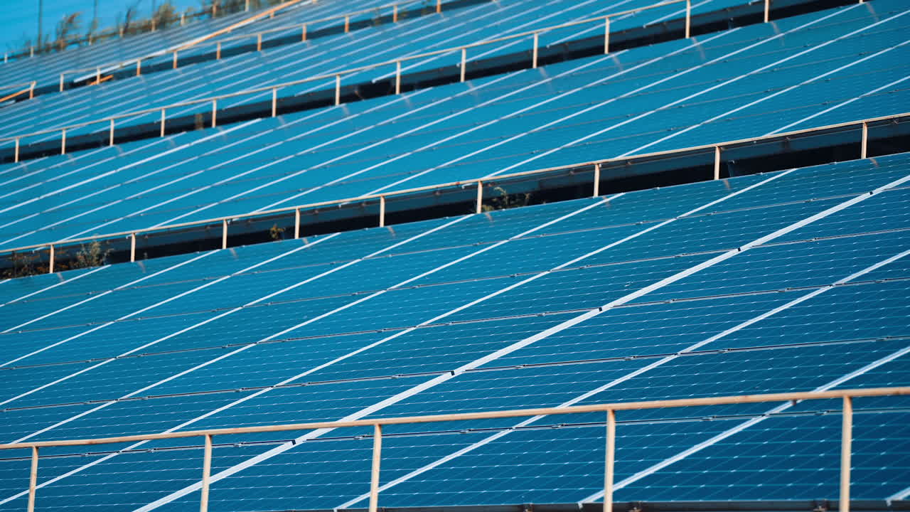 Solar panels stand in a row in the fields of green energy landscapes. Alternative sunlight energy technology.