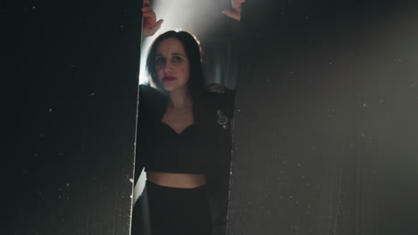 dramatic portrait of a woman in a black outfit, partially visible with a radiant backlight shining as the camera zooms out