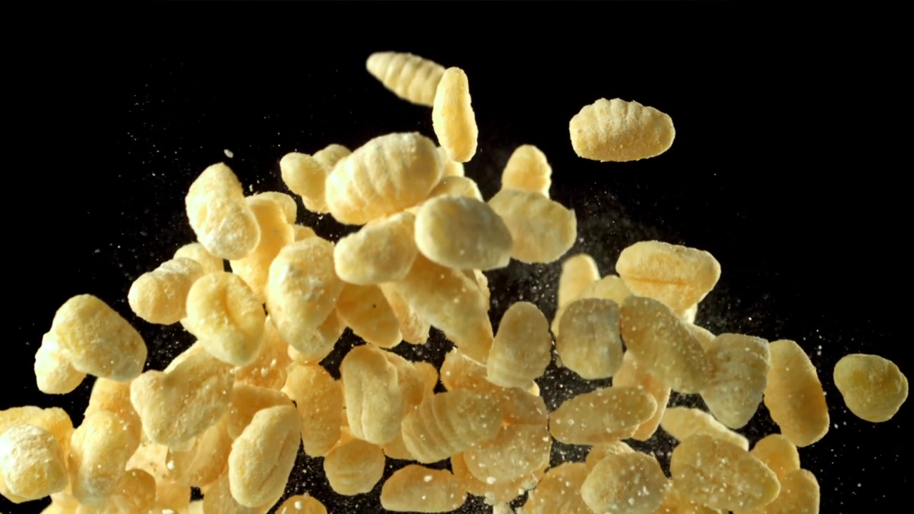 Gnocchi che lievitano al rallentatore con polvere di farina su sfondo nero