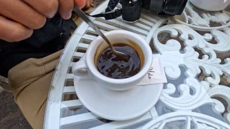 person stirring coffee at outdoor café