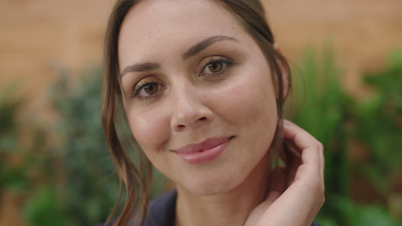 retrato en primer plano de una joven hermosa mujer caucásica sonriendo amigablemente corriendo con la mano a través del cabello buscando feminino inocente