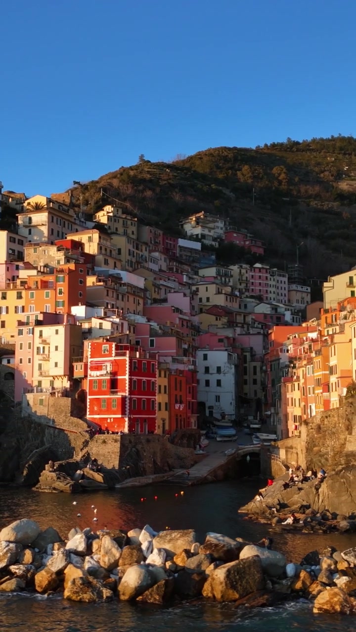 Vue orbitale par drone des maisons colorées de Riomaggiore, du port et du brise-lames rocheux au coucher du soleil, Cinque Terre, Italie