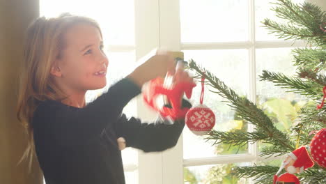 young girl hanging decorations on christmas tree