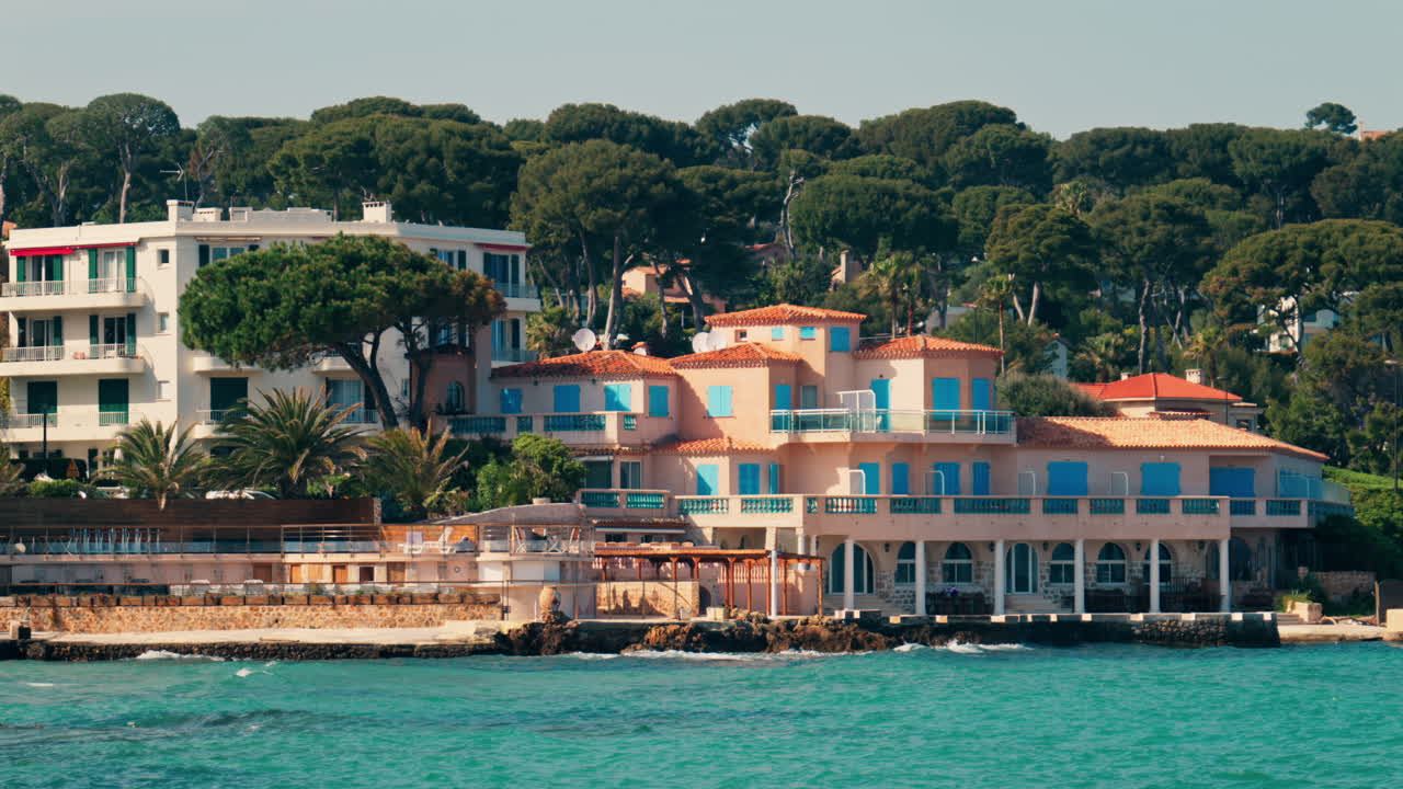 Distant view of multiple villas on the shore with the waves of the sea crashing on the rocks