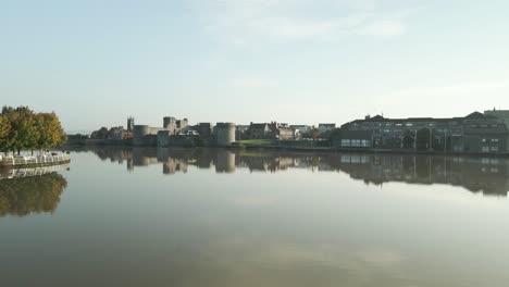 king john's castle and limerick cityscape reflected on the calm river shannon under clear skies