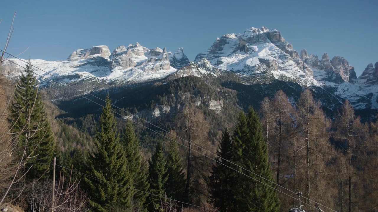 Cabine della funivia in un paesaggio montano innevato con foresta, ripresa statica a mano. Trasporto in gondola di una stazione sciistica che si muove orizzontalmente sopra un bosco di conifere verde