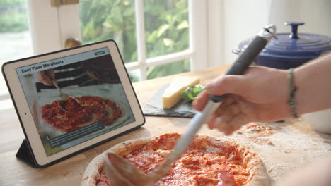 Person-Following-Pizza-Recipe-Using-App-On-Digital-Tablet