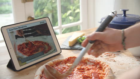 persona que sigue la receta de la pizza usando una aplicación en una tableta digital