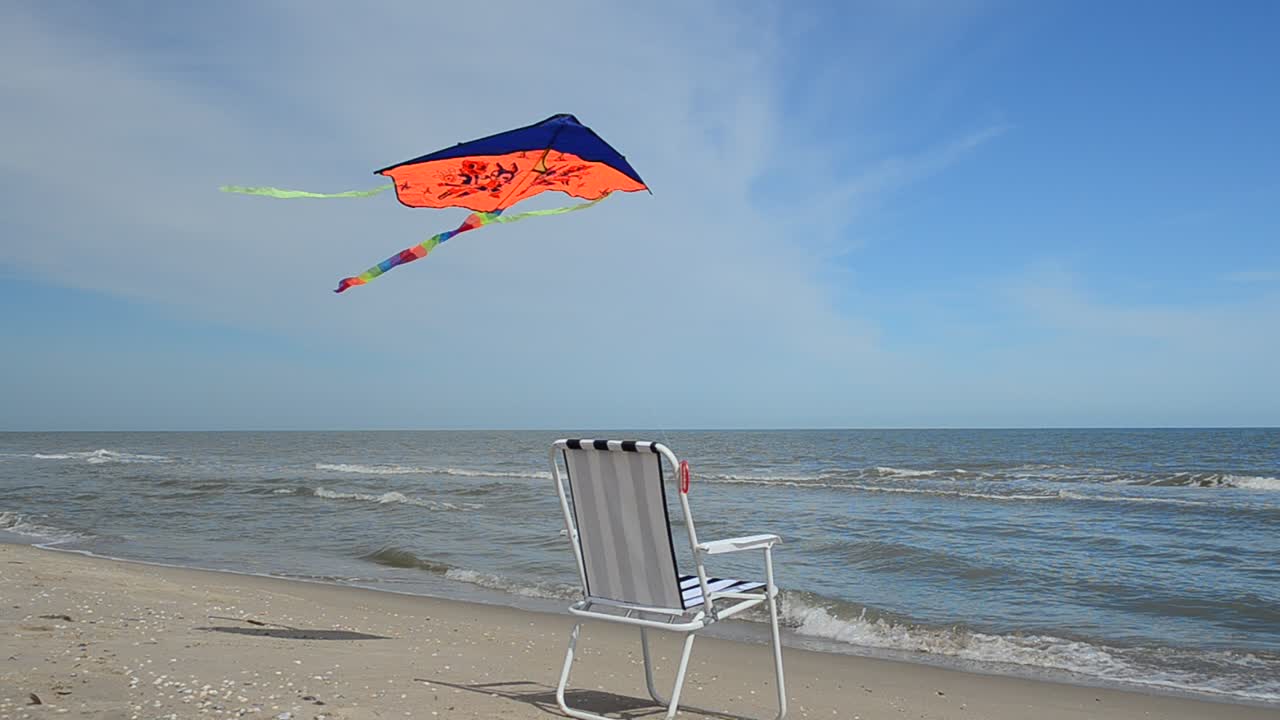 Liggestol på stranden, havet og en drage. Sommertid ved strandkanten
