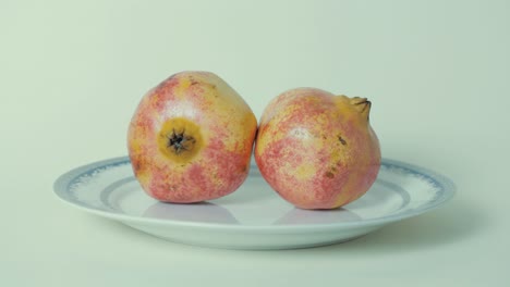 ripe pomegranate fruit on plate against white background