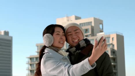 loving asian couple in winter clothes taking selfies