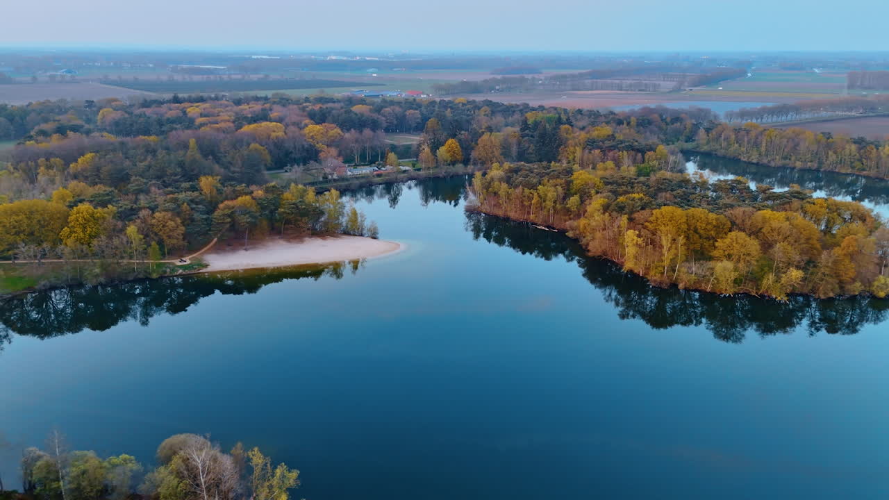 Serene lake view in Netherlands. Aerial view of a serene lake framed by colorful autumn trees in the Netherlands at dusk
