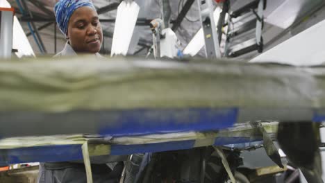 african american female car mechanic using a grinder on the side of a car