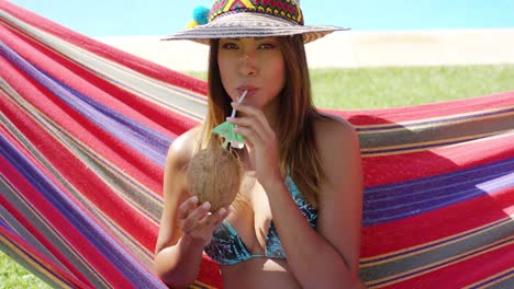 mujer con bebida de coco y sentada en una hamaca