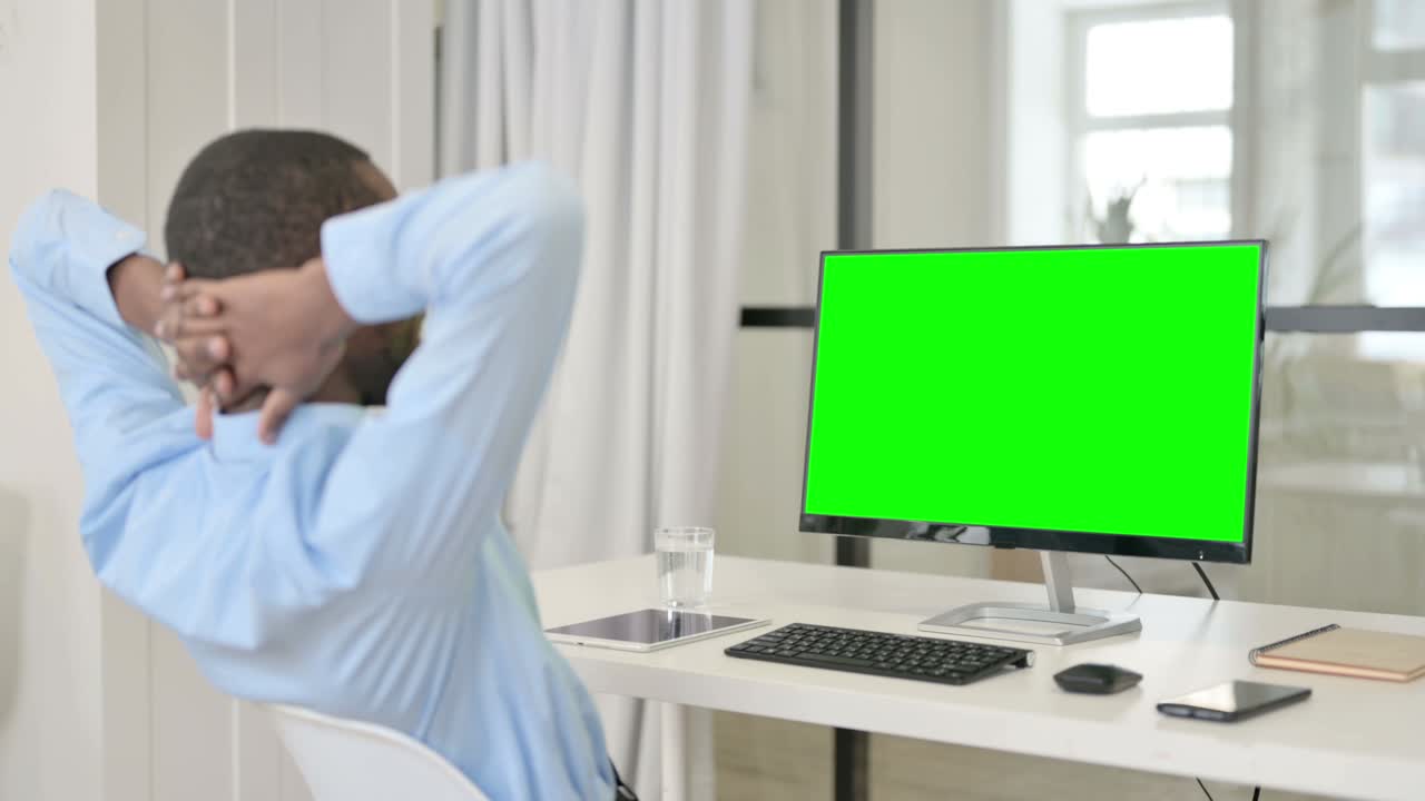 hombre de negocios descansando mientras usa el escritorio con pantalla clave de croma verde