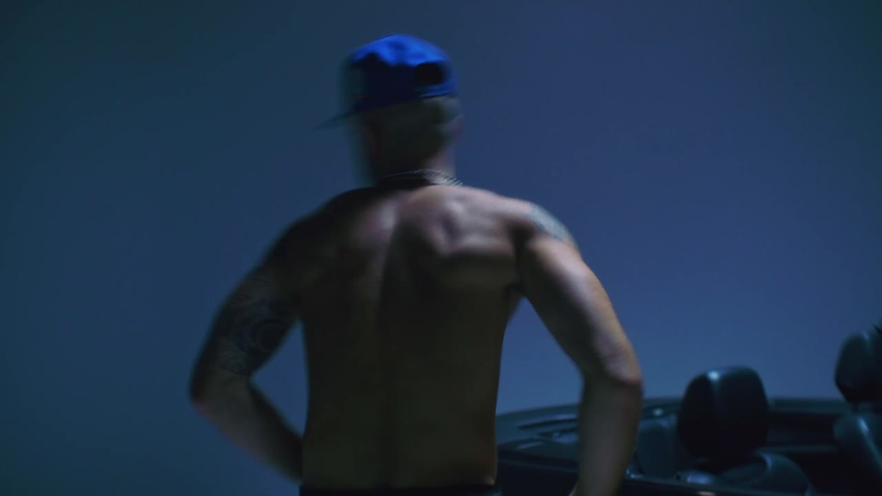 Hiphop dancer freestyle dancing in a studio in front of a sports car.