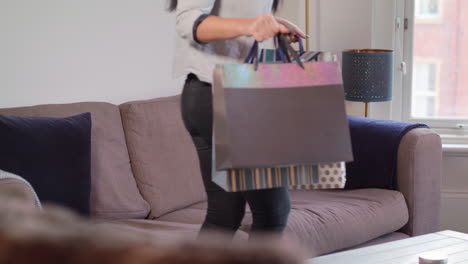mujer joven se sienta en el sofá después de un exitoso viaje de compras, en cámara lenta