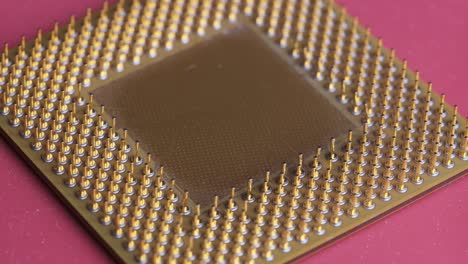 the old computer processor cpu with gold plated contacts spins on red background