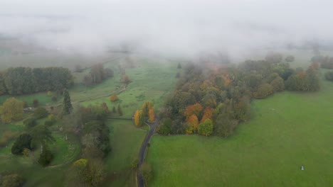 Volando-Hacia-Un-Banco-De-Niebla-Con-árboles-Y-Campos-De-Colores-Otoñales-Debajo