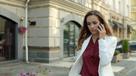 worried businesswoman receiving bad news by mobile phone outdoors