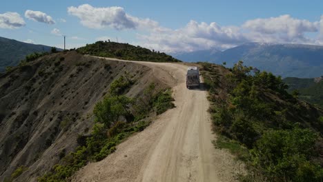 Drone-footage-of-camper-van-driving-on-a-dirt-trail-in-the-Trebeshinë-Dhëmbel-Nemërçkë-mountain-range-towards-Permet,-Albania