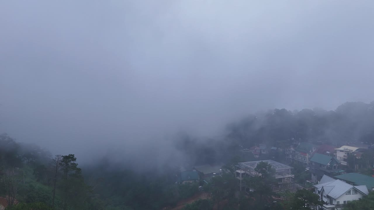 Misty landscape with buildings and trees shrouded in fog