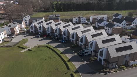 aerial sweep of gable-front solar townhouses curving around central lawn depicting community-oriented sustainable estate design