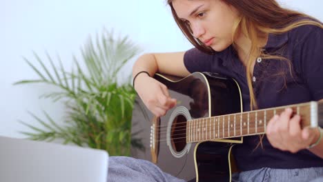 young woman with laptop playing guitar