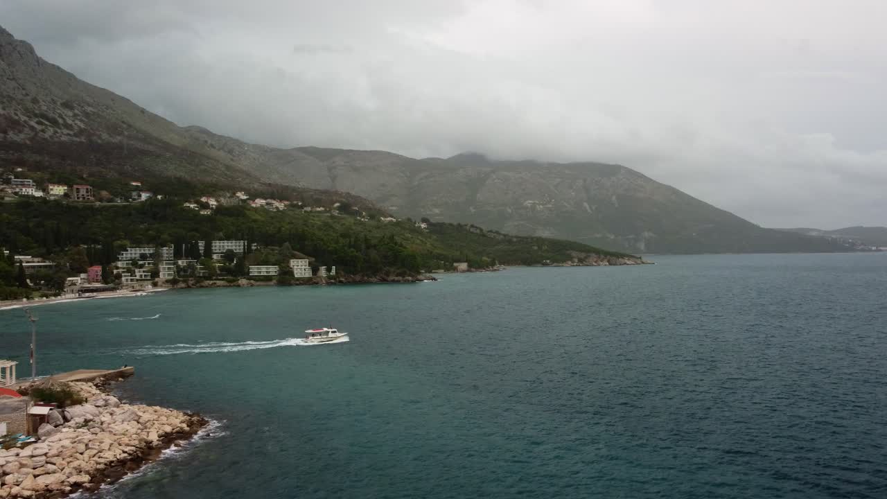 Drone 4k footage of a small ferry leaving Mlini Harbour heading out and then panning back around to Mlini Harbour, Croatia