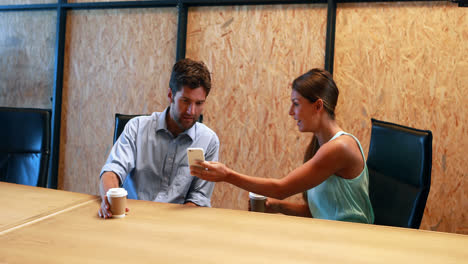 businesswoman showing mobile phone to coworker