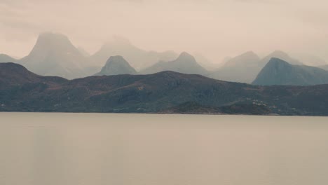 capas de cadenas montañosas envueltas en espesa niebla torre por encima del fiordo tranquilo