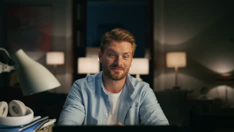 Positive-man-reading-desktop-at-dark-interior-closeup.-Person-remote-workplace