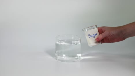 sequential pouring of sugar into a glass of water