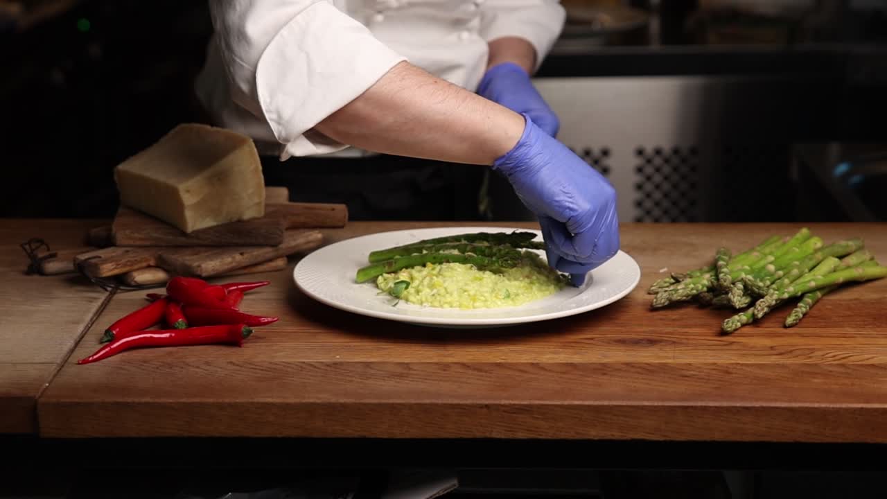 Chef che impiattano un risotto agli asparagi freschi in una cucina professionale