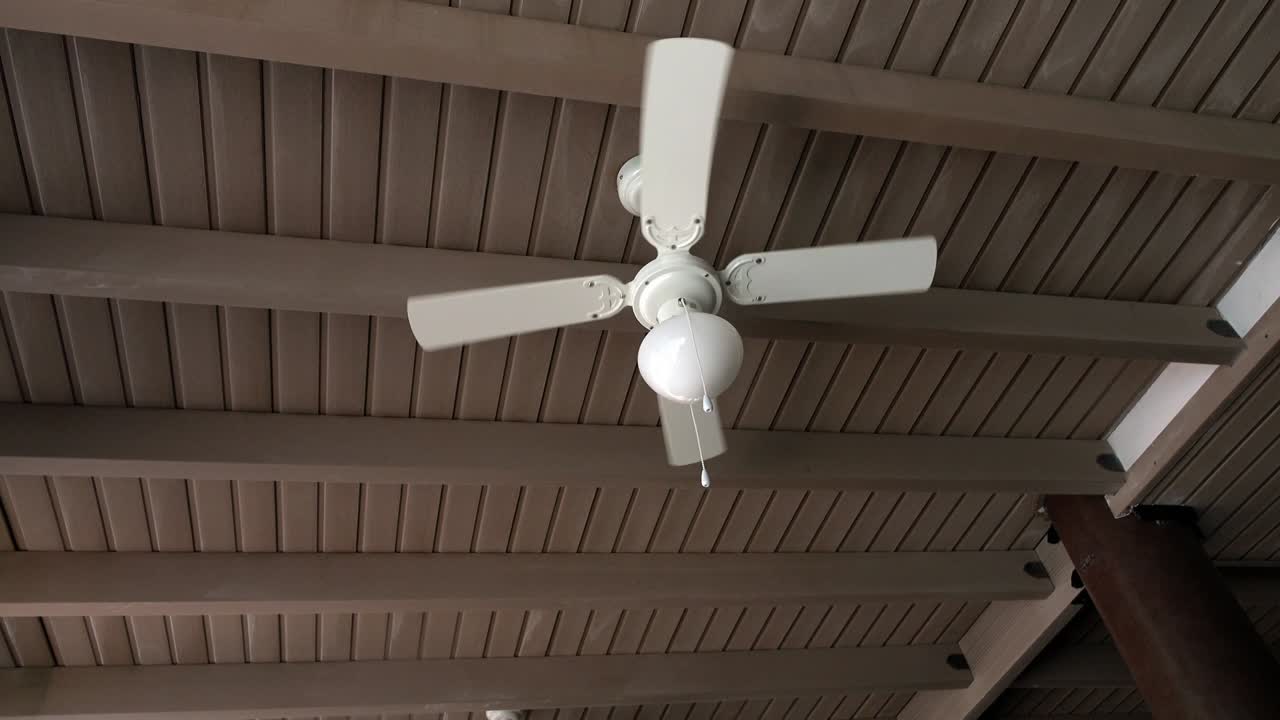 ventilador de techo girando en una cafetería con techo de paja.