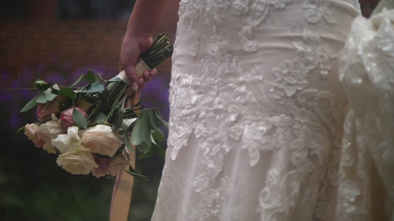 sposa in abito che tiene mazzo di fiori