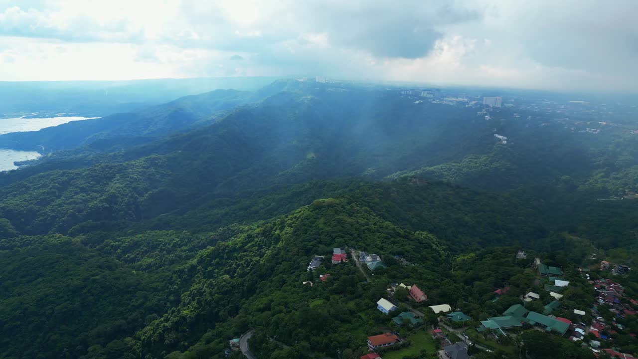 A pull-back wide aerial of mist-covered forested hills and lush greenery in Talisay, Batangas, Philippines