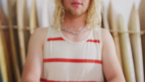 caucasian male surfboard maker holding one of the surfboards and looking to camera