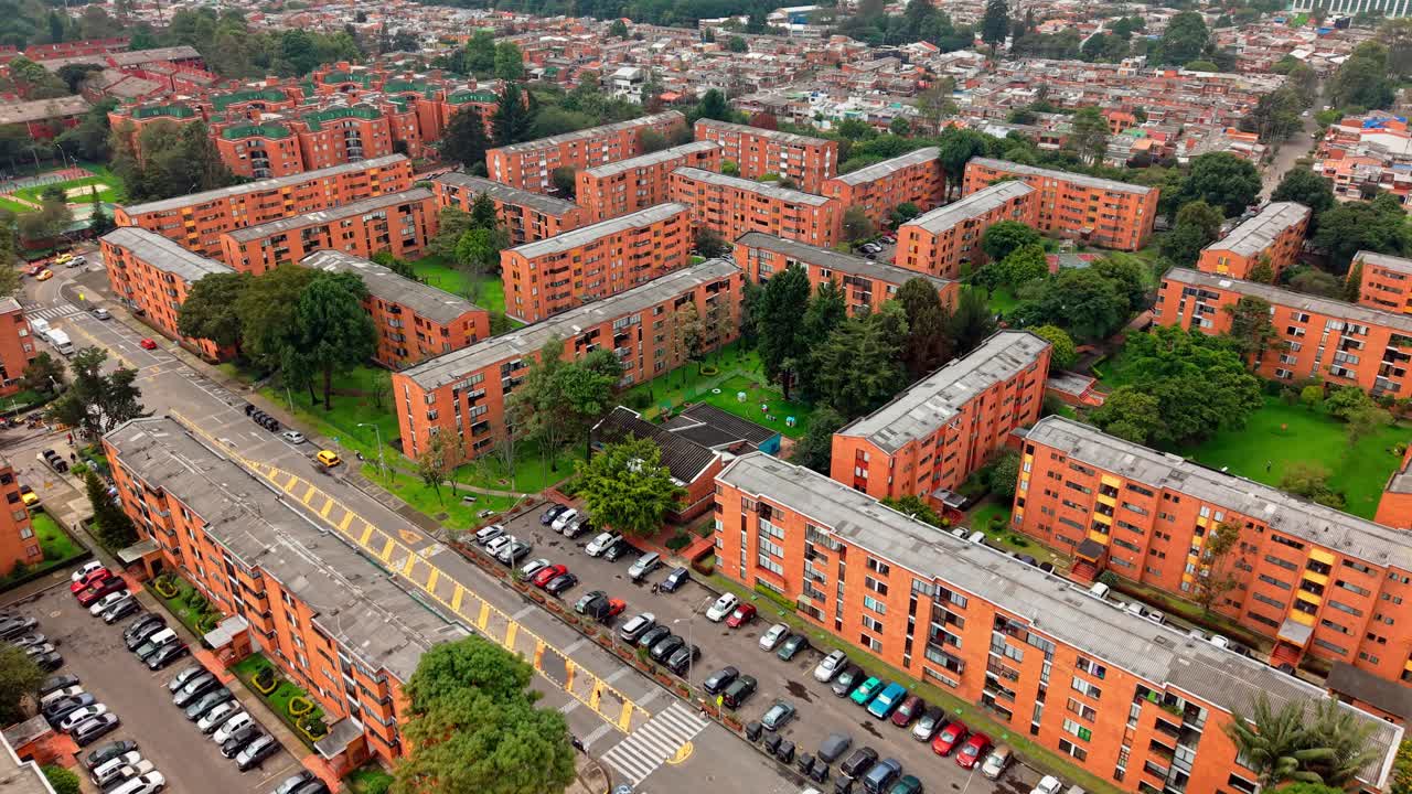 Drone view of orange buildings, vegetation, and roads in Teusaquillo, Bogotá, with distant cityscape.