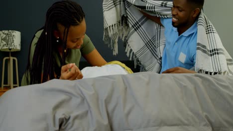 front view of young black parents playing with their son on bed in a comfortable home 4k
