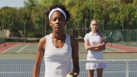 video of diverse female tennis players standing on court and holding rackets