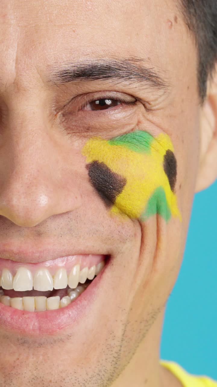 Mann mit einer auf das Gesicht gemalten jamaikanischen Flagge, der lächelt