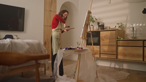 woman painting in a combined living area and kitchen studio