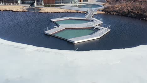 vã¶k geothermal outdoor spa with floating infinity pools in natural lake, reveal shot